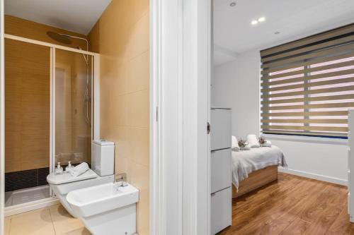 a bathroom with a sink and a toilet and a bed at Plaza del Carmen in Gijón