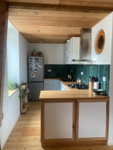 Il comprend une cuisine équipée d'un comptoir en bois et d'un réfrigérateur. dans l'établissement T3 Briançon avec pan d'escalade, à Briançon