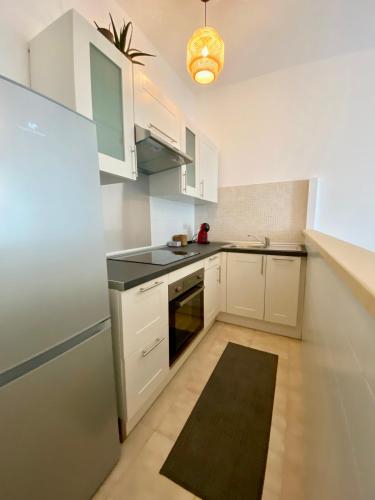 une cuisine avec des armoires blanches et un comptoir noir dans l'établissement Au coin du pin, à Menton