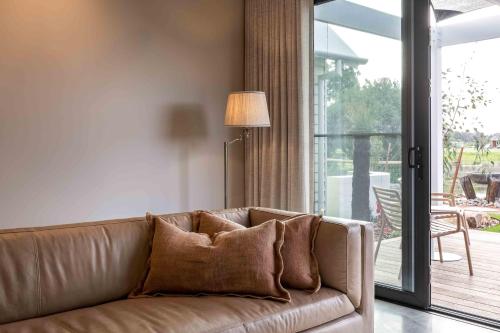 a brown couch in a living room next to a sliding glass door at Birdnest Galah in Witchcliffe