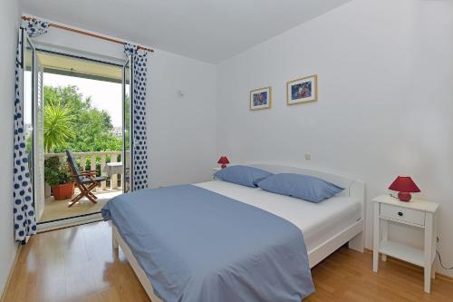 a white bedroom with a bed and a balcony at Apartments Mićić in Hvar