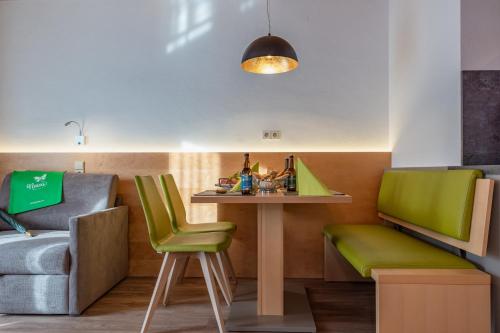 a living room with a table and green chairs at nawu apartments & Restaurant in Hermagor
