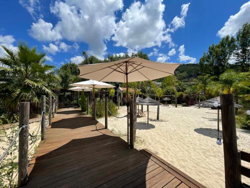 a wooden boardwalk with an umbrella on the beach at Duas Quintas Areal in Guimarães