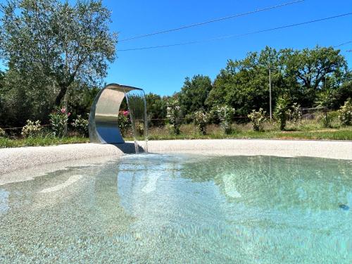 a swimming pool with a fountain in the middle of a road at Agriturismo San Ansanino- Piscina con spiaggia-Aria condizionata in Pari