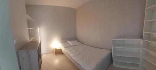 - une petite chambre blanche avec un lit et une lumière dans l'établissement STUDIO TERRASSE OCEAn, à La Rochelle