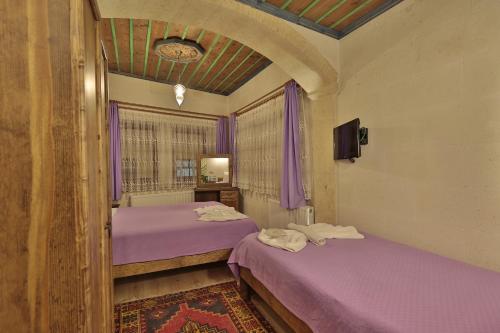 two beds in a room with purple sheets at Relic House in Goreme