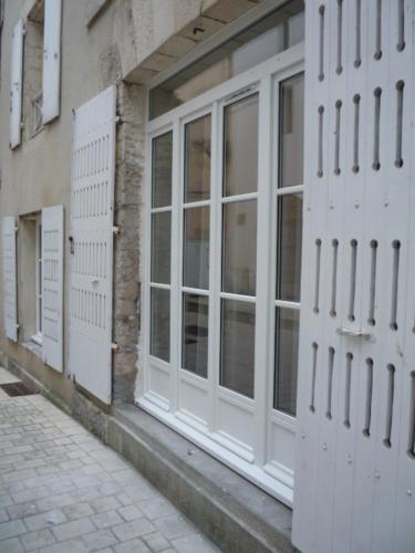 un bâtiment avec des portes blanches sur le côté d'une rue dans l'établissement Demain l'Océan Hyper-centre La Rochelle - Ménage, Draps et serviettes optionnels non compris dans le prix affiché, à La Rochelle