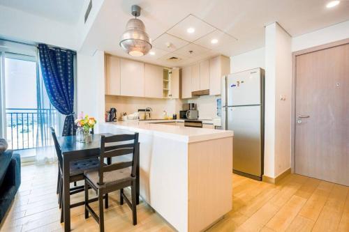 a kitchen with a table and a refrigerator at Family Escape 3BR plus Maids Elegant Yas Island907W4 in Abu Dhabi