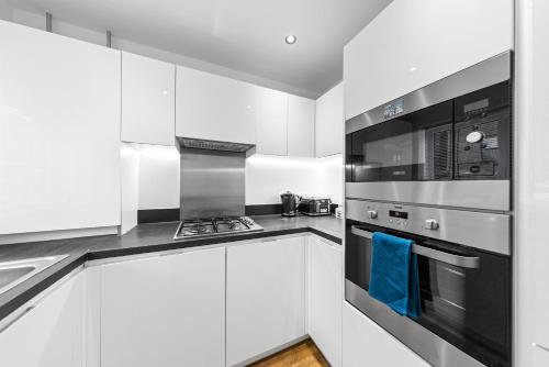 a kitchen with white cabinets and a stove top oven at THE OAK - An Elegant 2 Bedroom House in Dartford - London Zone 8 in Dartford