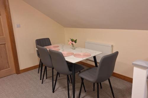 a table with four chairs and a vase of flowers on it at Ballnamona house in Cong