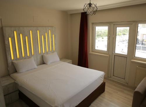 a bedroom with a bed with white sheets and two windows at Ege Premium Hotel in Afyon