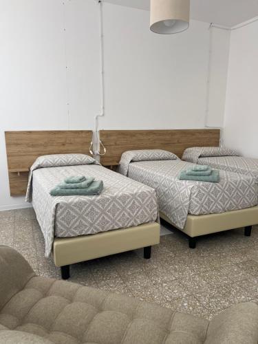 two twin beds in a room with a couch at Civico 9 in Bonorva