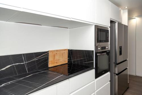 - une cuisine avec des murs noirs et blancs et un réfrigérateur dans l'établissement Appartement Paris - La Défense, à Nanterre