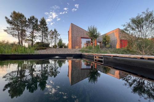 a house is reflected in a body of water at Natura Natura in Paredes