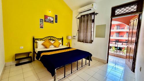 a bedroom with a bed and a yellow wall at Muffy’s Vacation Apartment in Baga