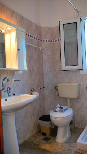 a bathroom with a sink and a toilet and a mirror at Studios Evgenia Parga in Parga