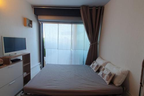 - une chambre avec un lit, une fenêtre et une télévision dans l'établissement 1er ligne piscine au couchant, à La Grande Motte