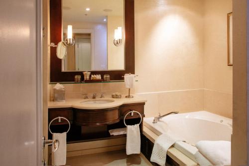 a bathroom with a tub and a sink and a mirror at Windsor Arms Hotel in Toronto