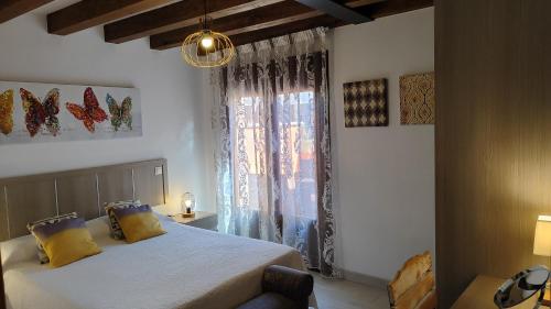 a bedroom with a bed with yellow pillows and a window at Apartamentos La Alborada Medieval in Ayllón