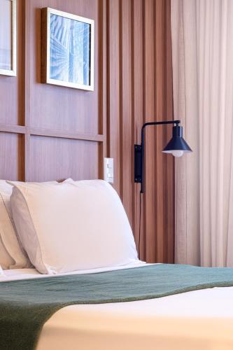 a bedroom with a bed and a lamp at PALMAS EXPERIENCE - APARTAMENTO CONTEMPORÂNEO, vista serra, na quadra do shopping in Palmas