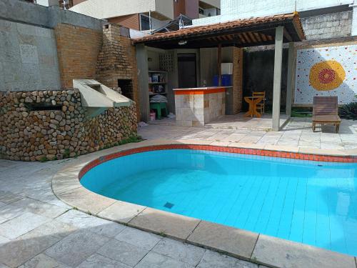 a swimming pool in a yard with a stone wall at Rô Hostel Cabo Branco in João Pessoa