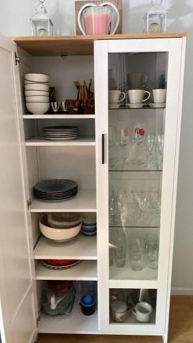 une armoire blanche remplie de vaisselle et d'assiettes dans l'établissement Le Coquelicot de Luchon, à Luchon