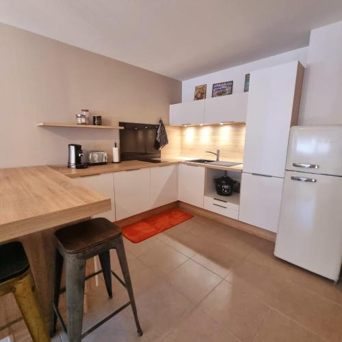 une cuisine avec des armoires blanches et une table en bois dans l'établissement Ce jolie appartement de 45 m2, à Perpignan