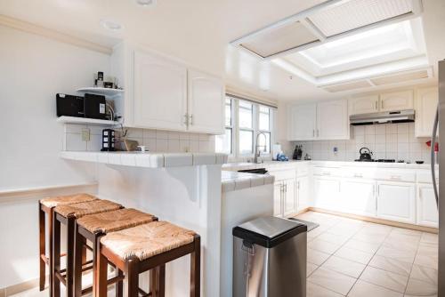 a white kitchen with white cabinets and stools at Luxury Penthouse with Elevator - Sleeps 10+ - Family Friendly Sun / Surf / Sand in San Diego