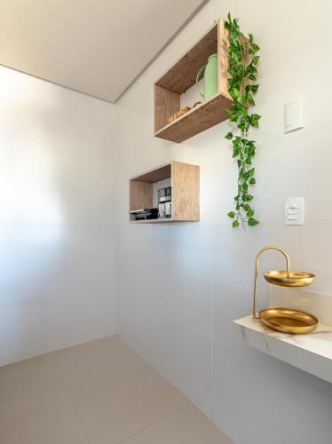 a bathroom with white walls and a gold sink at PALMAS EXPERIENCE - APARTAMENTO SUBLIME, vista incrível, em frente ao shopping in Palmas