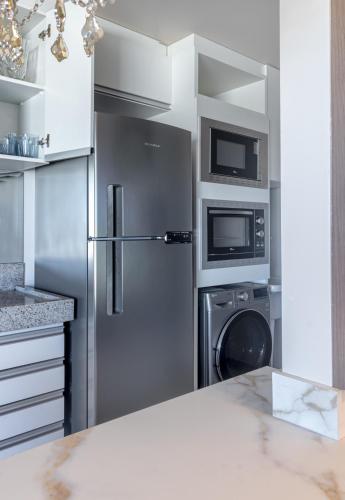 a kitchen with a refrigerator and a washer and dryer at PALMAS EXPERIENCE - APARTAMENTO SUBLIME, vista incrível, em frente ao shopping in Palmas