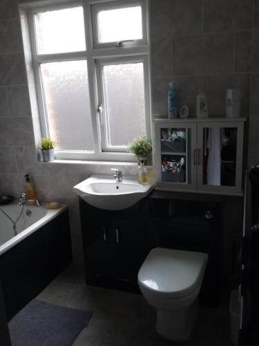 a bathroom with a sink and a toilet and a window at medium sized room in my bungalow in Great Clacton