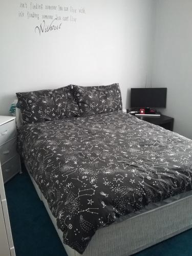 a bedroom with a bed with a black comforter at medium sized room in my bungalow in Great Clacton