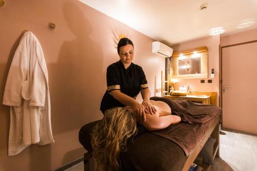 a woman sitting on a bed in a room at Plaza Madeleine & Spa in Sarlat-la-Canéda