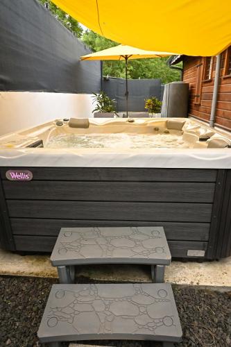a large bath tub with an umbrella and a bench at Villa Citala avec Piscine et Jacuzzi privé in Le Marin