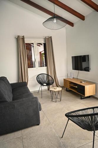 a living room with a couch and a tv at Villa Citala avec Piscine et Jacuzzi privé in Le Marin