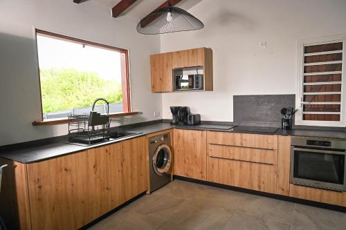 a kitchen with wooden cabinets and a sink and a dishwasher at Villa Citala avec Piscine et Jacuzzi privé in Le Marin