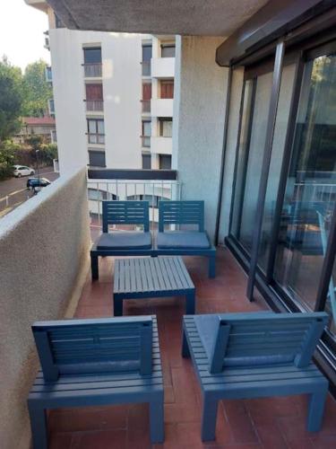 trois bancs bleus assis sur le balcon d'un immeuble dans l'établissement Appartement proche de la mer, à Perpignan