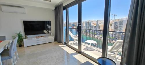 a living room with a television and a balcony at Luxury Sea Front at Spinola Bay St Julians in St Julian's