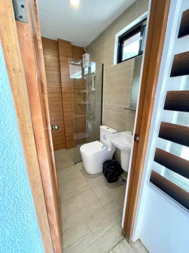a bathroom with a toilet and a glass shower at Elmarie Beach Resort in San Fabian