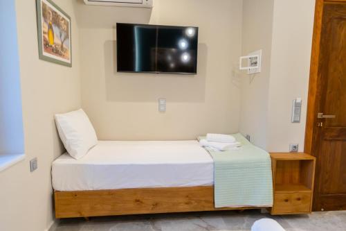a bedroom with a bed and a tv on the wall at Armenopetra View Gerolimenas in Gerolimenas
