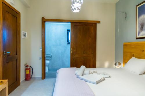 a bedroom with a white bed and a bathroom at Armenopetra View Gerolimenas in Gerolimenas
