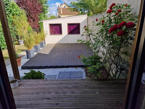 une passerelle en bois avec des fleurs rouges et un bâtiment dans l'établissement Le Chalet Marceau, à Carrières-sur-Seine