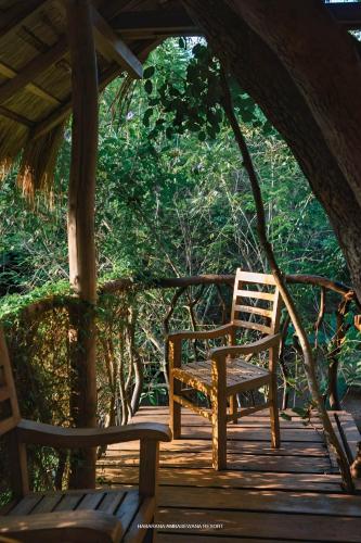 a wooden bench sitting on a wooden deck with trees at Habarana Tree House Ambasewana Resort in Habarana