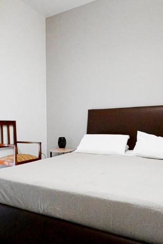 a bedroom with a large white bed and a chair at Miro B&B in Lecce