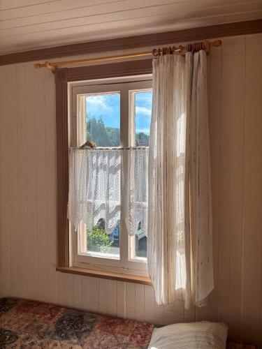 a bedroom with a window with curtains and a bed at Auberge du Jardin in Petit-Saguenay