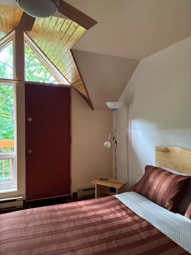 a bedroom with a bed and a large window at Auberge du Jardin in Petit-Saguenay