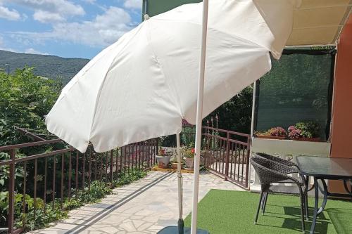 a white umbrella on a patio with a table and chairs at Apartment Radanović-Beaches 5 min walking in Cres