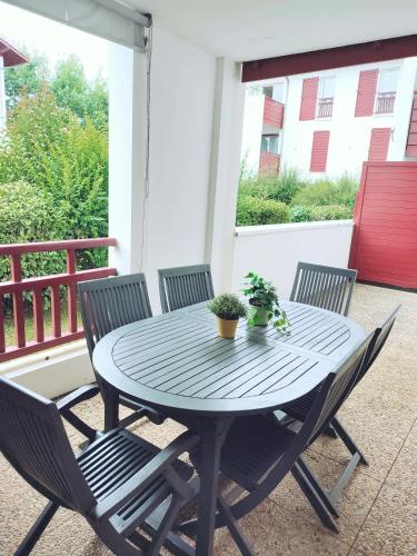 une table bleue et des chaises sur un porche avec une table et des plantes dans l'établissement Beau T2 proche plages et montagnes du Pays-Basque, à Ahetze