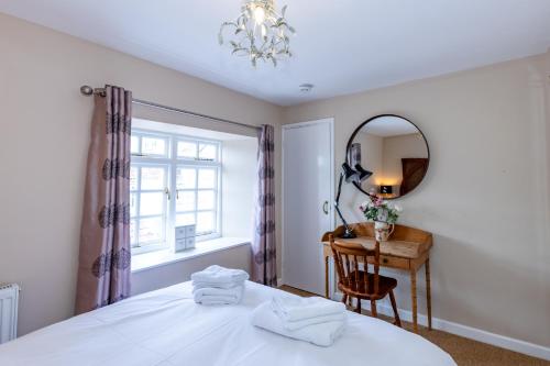 a bedroom with a bed and a desk and a mirror at The Snug - A Quaint Mews Cottage City Centre in Wells