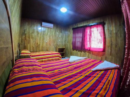 a bedroom with two beds with a striped blanket at El Retiro Lanquin in Lanquín